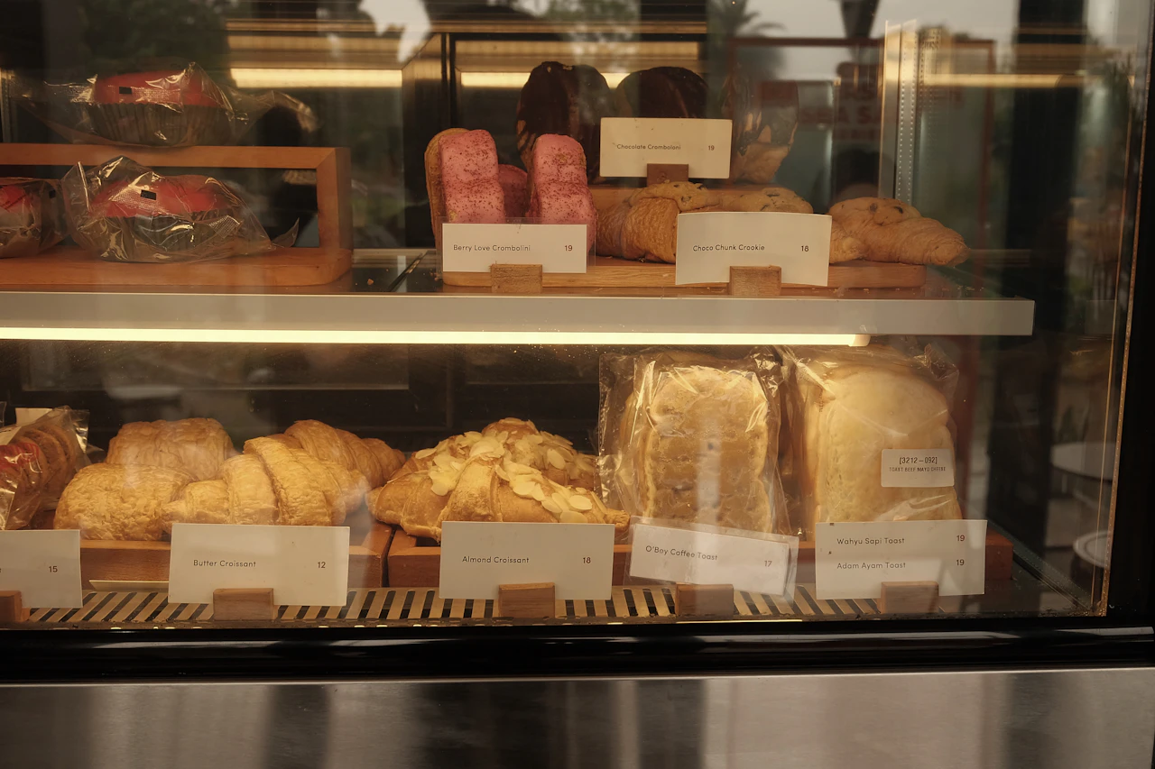 A bakery display case filled with breads and pastries, warm lighting