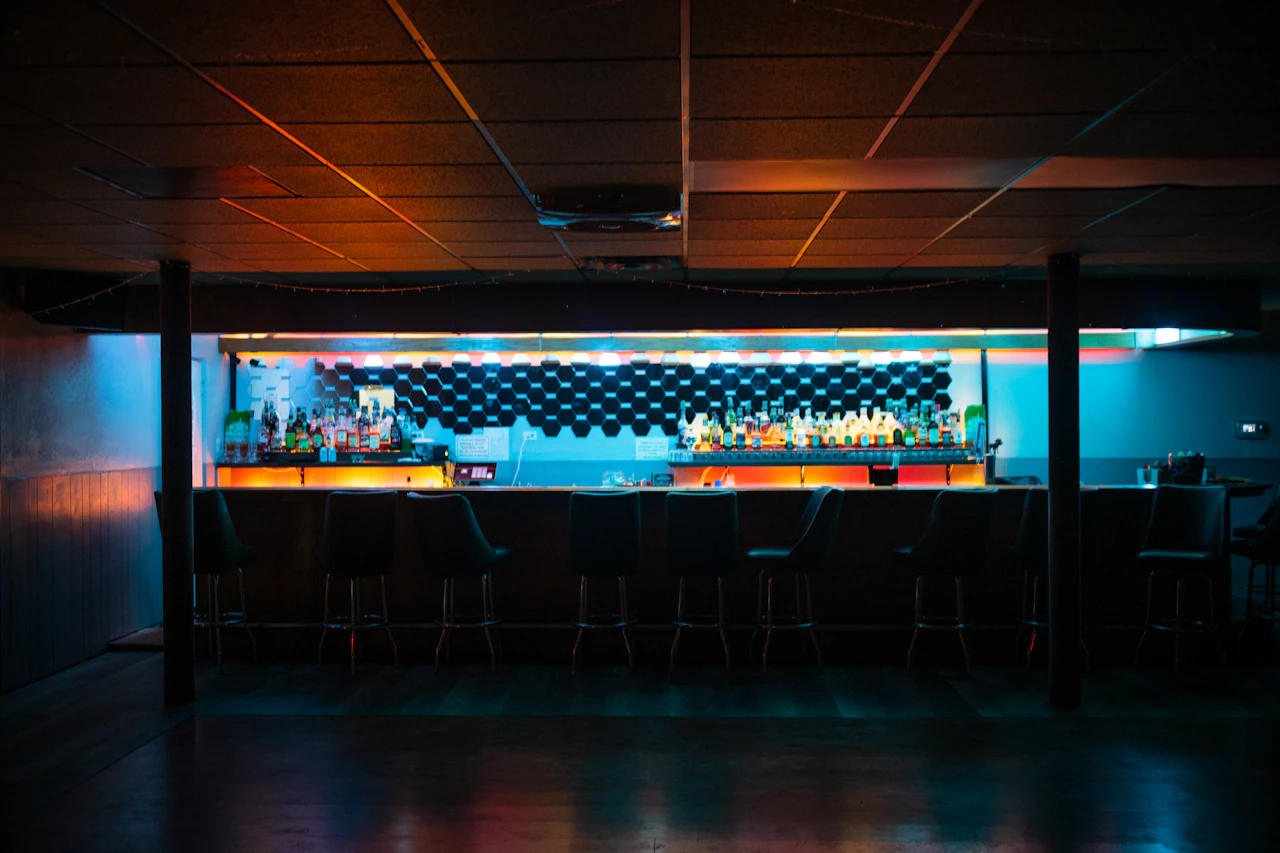 A bar operator at a small shop counter doing end-of-night paperwork with a closed sign behind him