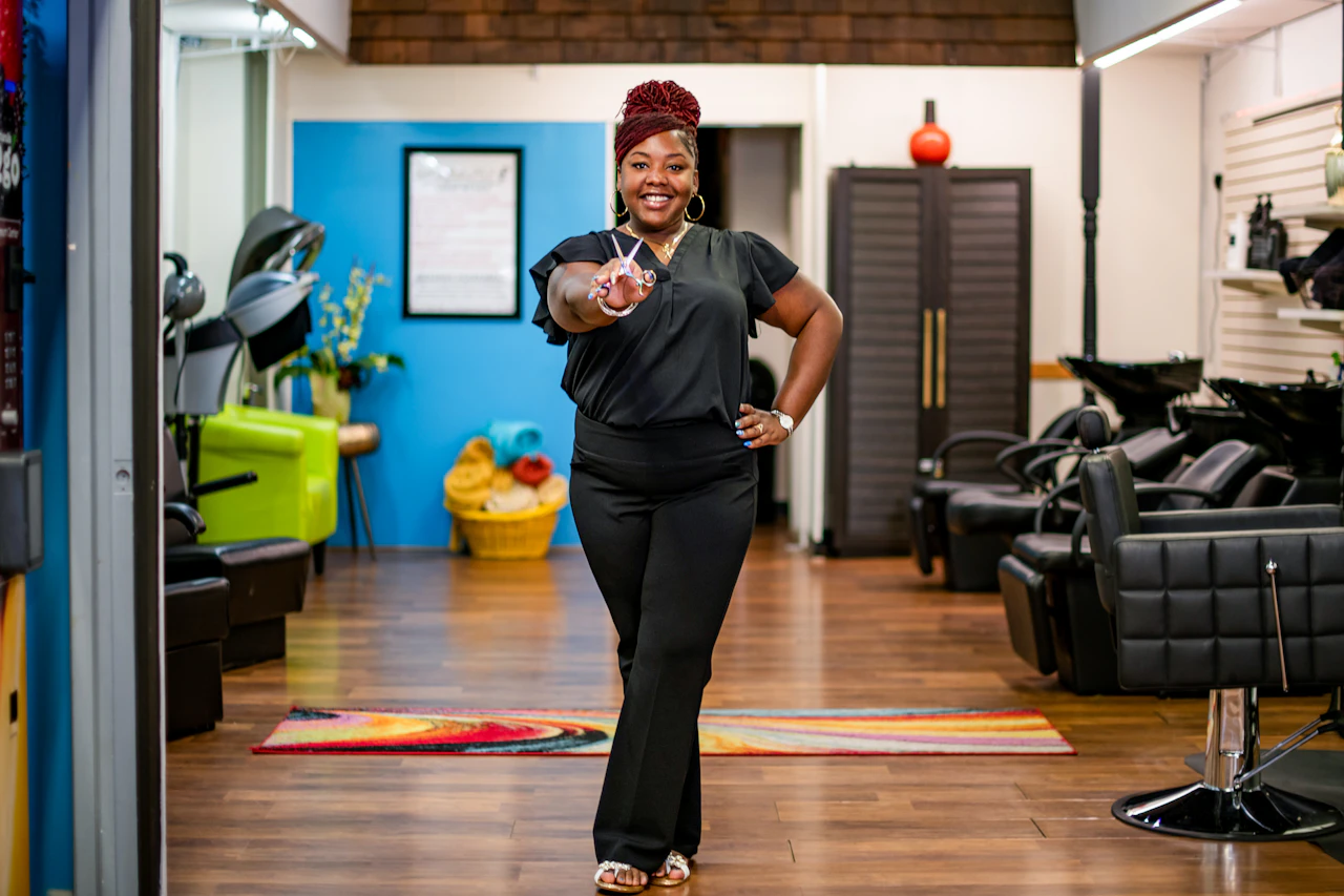 Salon owner standing in her shop with empty styling chairs in the background